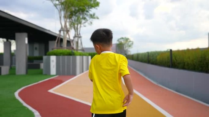 亚洲男孩在赛道上练习跑步