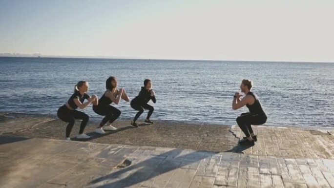 臀部锻炼。三位不同的女性与男性健身教练一起练习深蹲，一起在码头上训练
