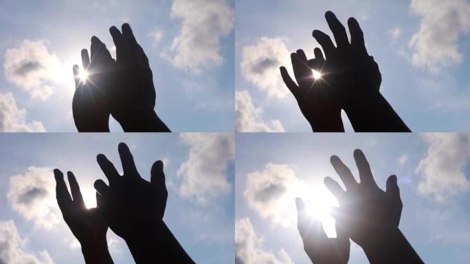 在蓝天背景上，人的双手与太阳光一起玩耍。