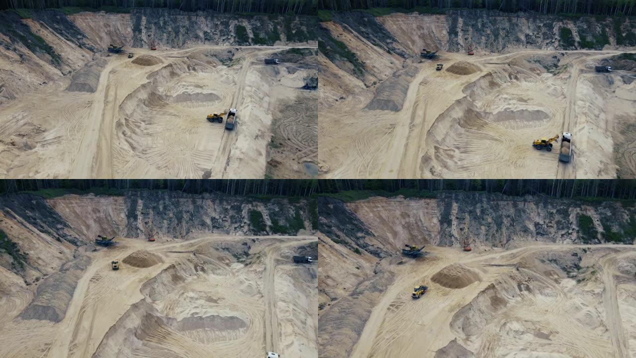 前端装载机在露天矿将沙子装载到自卸车中。颚式破碎机制砂生产线。在采石场工作的重型采矿机械。