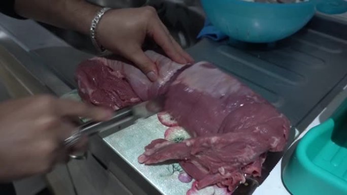 一名男子用刀割肉，用手在4k的厨房里准备烤架的特写镜头