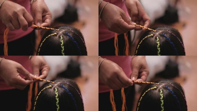 亚洲女孩被女人的手编织成多色的线。