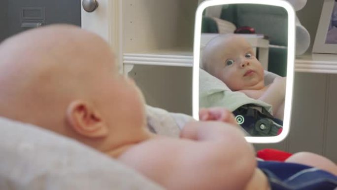 可爱的婴儿躺在家里镜子前的摇椅上，面对高加索人3个月大的新生婴儿特写。