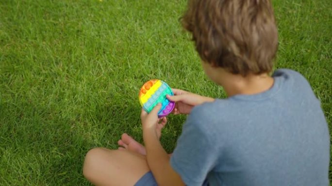 男孩玩流行玩具简单的酒窝，坐在街上。