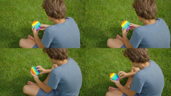 男孩玩流行玩具简单的酒窝，坐在街上。