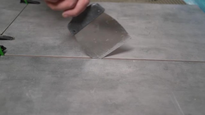 用刮刀清洁瓷砖之间的接缝。