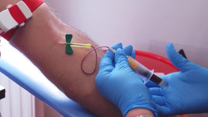 蓝色乳胶手套熟练的专业护士使用一次性静脉穿刺针采集高加索男性患者的血液样本并切换多个真空试管cont