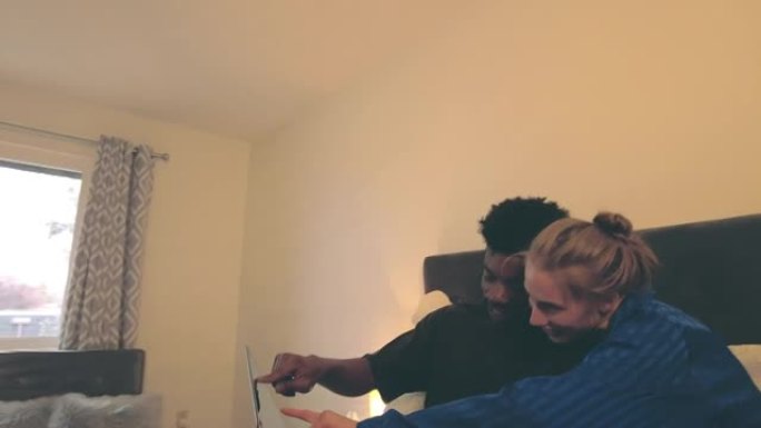 混合民族夫妇在现代卧室4k视频系列中与技术合作