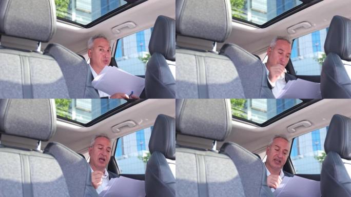 白发苍苍的富商坐在车辆后座上，在网上打电话
