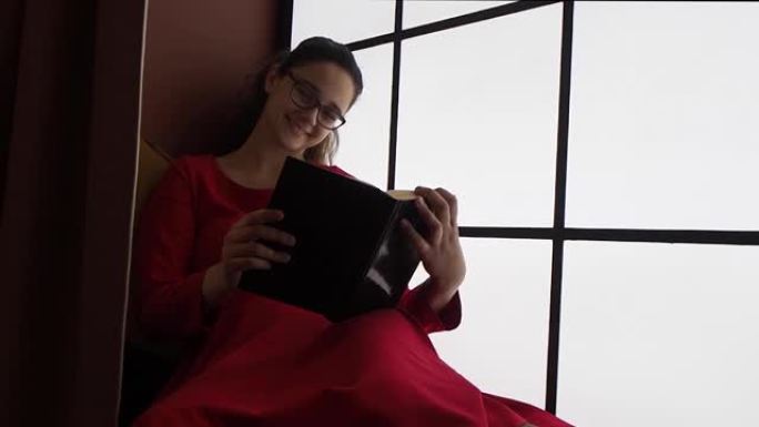 穿着红色连衣裙笑着的少女，靠窗的书