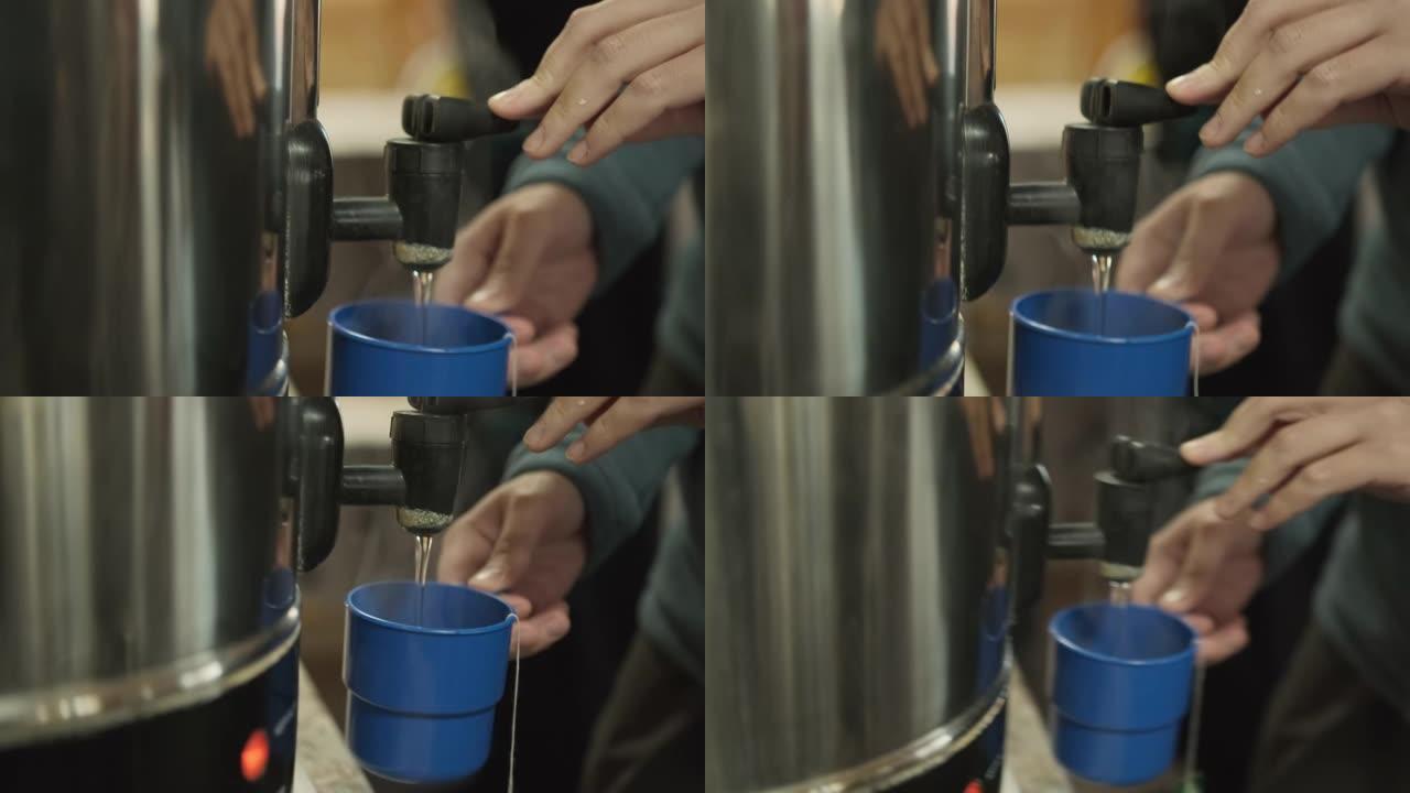 从热水器里，水被装满一个杯子。