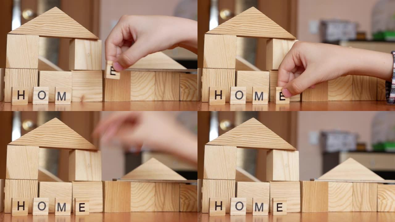 孩子正在玩耍，用立方体建造一座房子。孩子的手用木制立方体使单词回家。有创造力的孩子建造一座塔和一座房