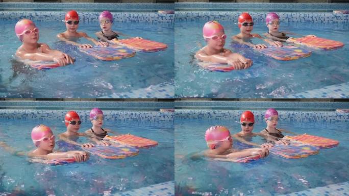 戴着游泳帽和眼镜的小孩在儿童游泳池学习游泳