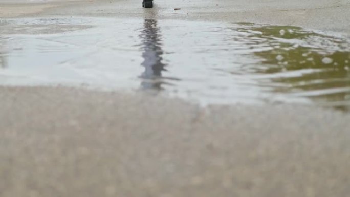 春雨过后，一个穿着黑色皮靴的女孩走过水坑，缓慢的mo