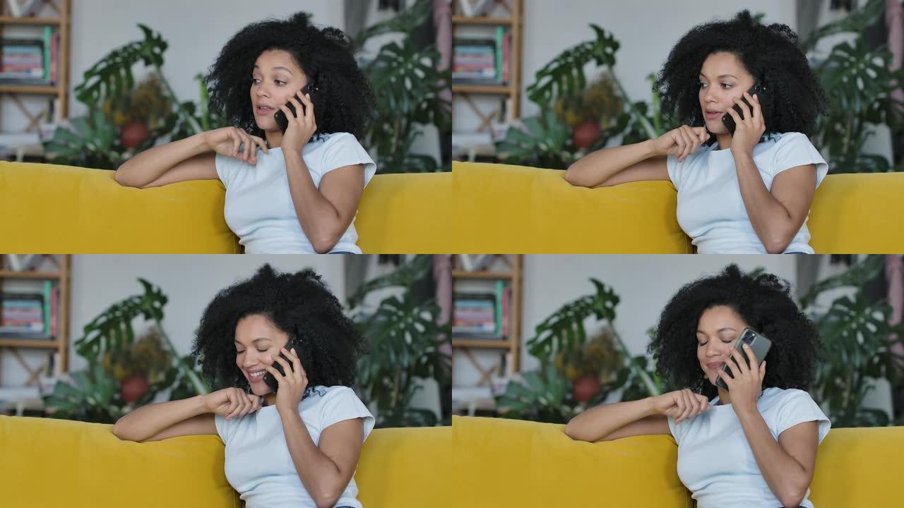 一位年轻的非洲裔美国妇女为手机聊天的肖像。黑发，卷发，坐在明亮的家庭房间里的黄色沙发上。特写。慢动作