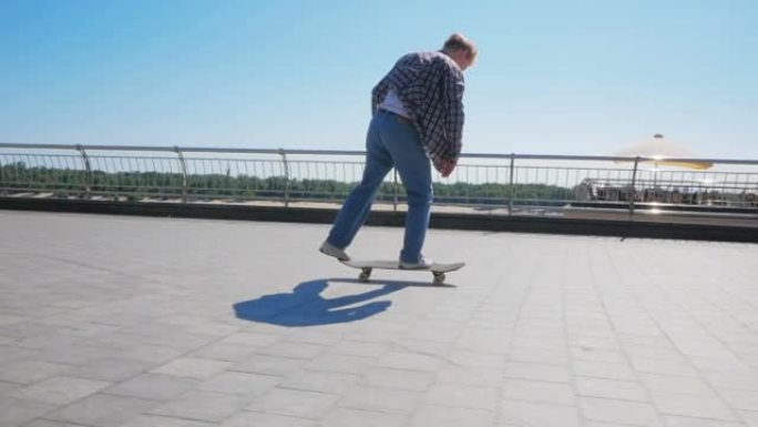一个年轻的千禧一代，在城市里无忧无虑地骑滑板。年轻有魅力的家伙正在骑滑板。专业滑板手沿着城市堤防骑滑