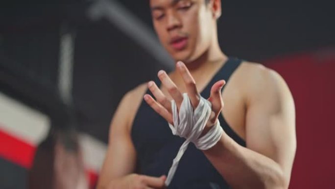 亚洲活跃英俊的运动员男子手拿运动包装手套在健身房锻炼。年轻的运动员拳击手在体育场进行拳击运动后充满信