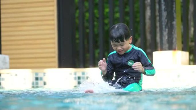 亚洲男孩在游泳池练习游泳和跳跃