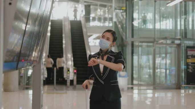 带防护面罩的年轻女乘务员在走到登机口之前再次检查到达离场板-股票视频