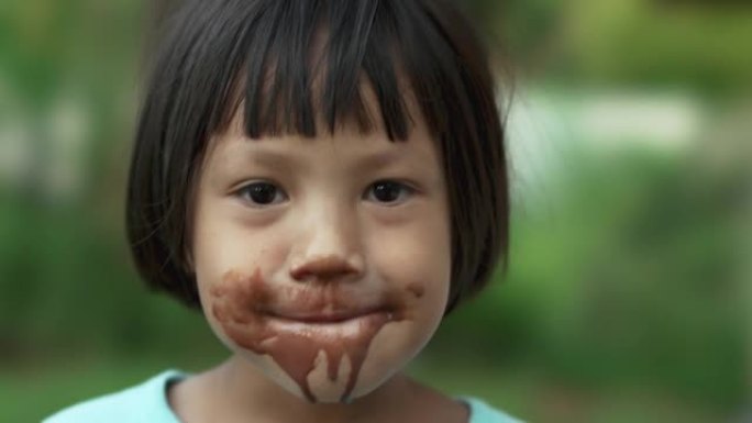 快乐微笑的亚洲儿童女孩乱吃巧克力冰淇淋。
