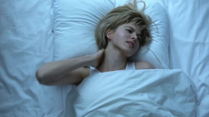 焦虑的女人按摩麻木的脖子躺在床上不舒服的睡眠条件