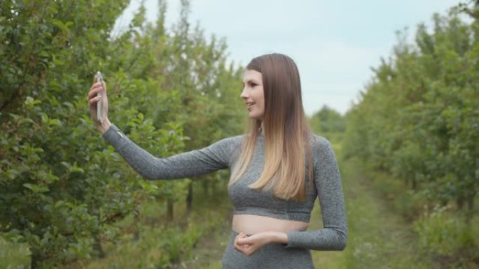 直播期间快乐的健身女人。一位现代体育女性在自然智能手机上拍照，录制视频博客。体育视频vlog。视频博