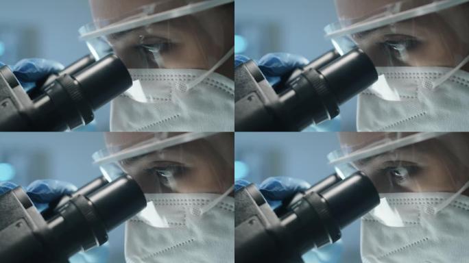 穿着防护服的女实验室科学家通过显微镜观察