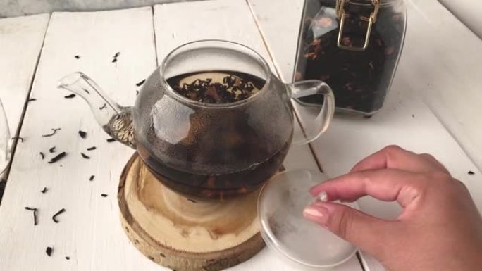 女孩手倒开水蛋羹玻璃茶壶配叶茶