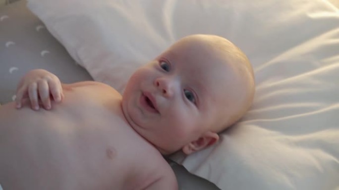 婴儿在婴儿床上打喷嚏，面对三个月大的男婴特写。