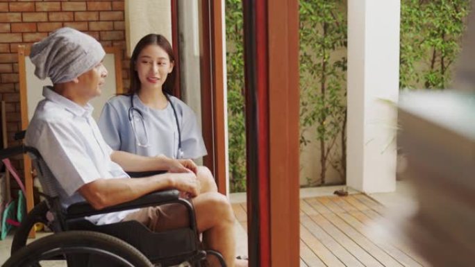 老亚洲老人坐在家里的轮椅上，看着窗外思考。孤独的老人独自在家度过一天。家庭人寿保险的概念。