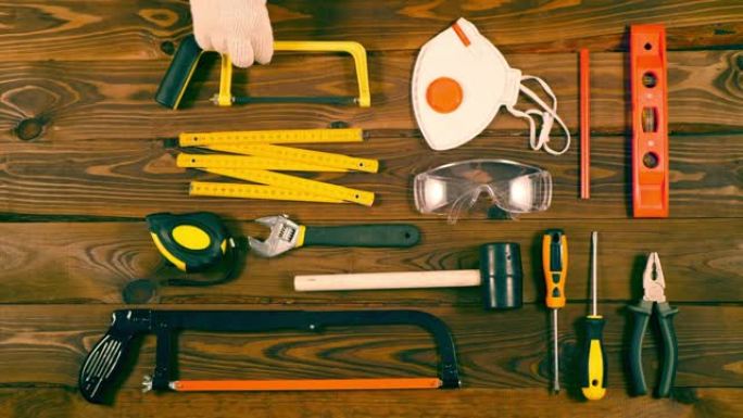 一名工人用漂亮的棕色木板将用于维修的建筑工具和设备放在桌子上。翻新概念。家庭维修的最佳工具。特写。顶