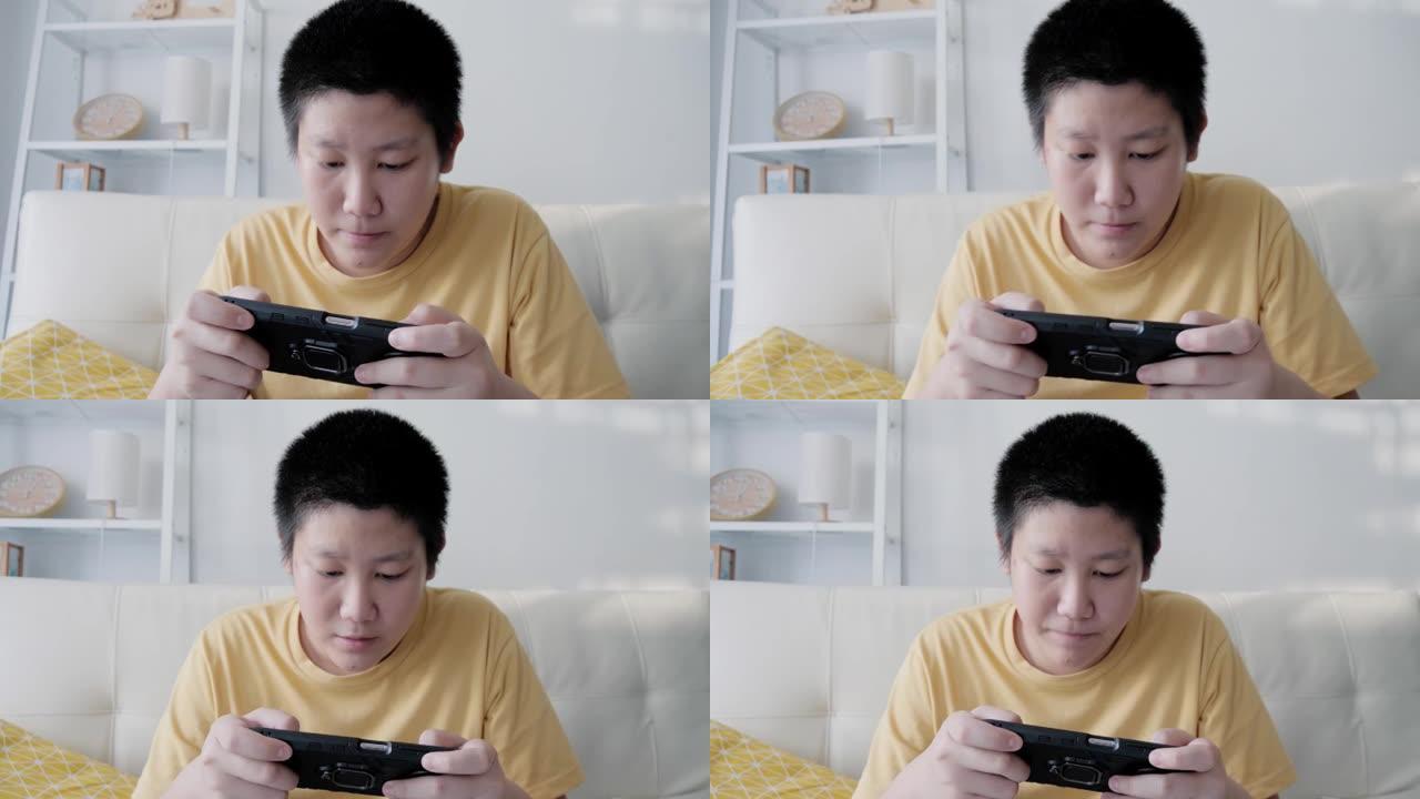 亚洲男孩在家沙发上玩在线手机游戏，生活方式概念。