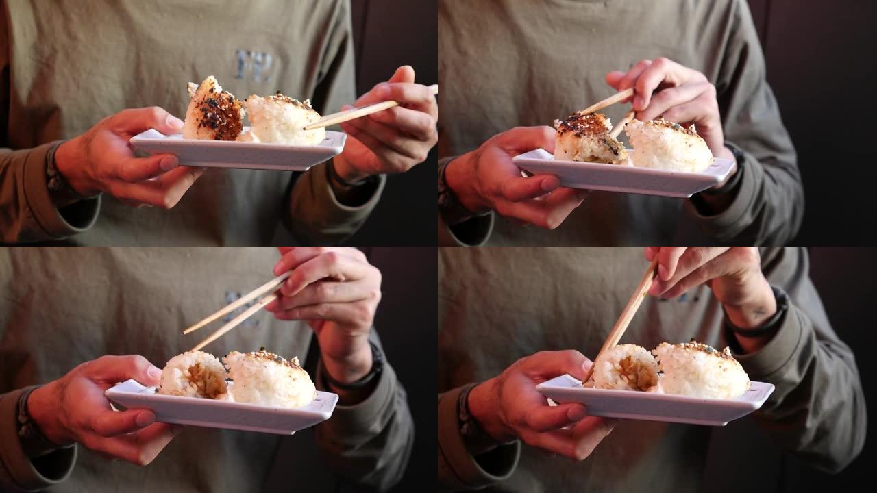 特写镜头，男子用筷子吃烤饭团的手持镜头
