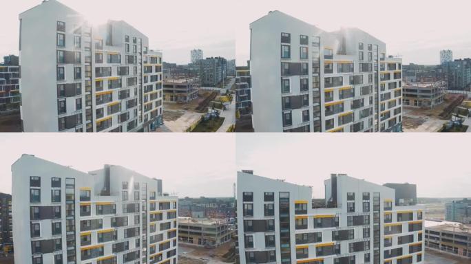 建筑工地，建筑工作流程现代化的公寓楼。未完成的结构城市公寓楼，白色立面，背景日落有斜屋顶和窗户，顶视