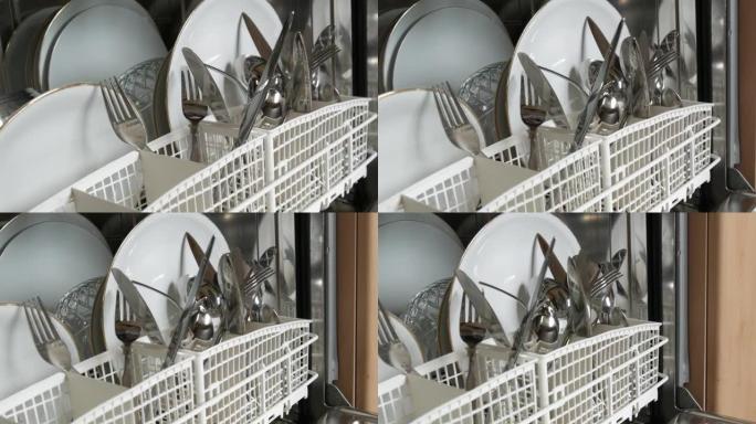 用洗碗机清洗新鲜洗过的盘子。盘子、锅、勺子、叉子、玻璃杯和杯子非常干净