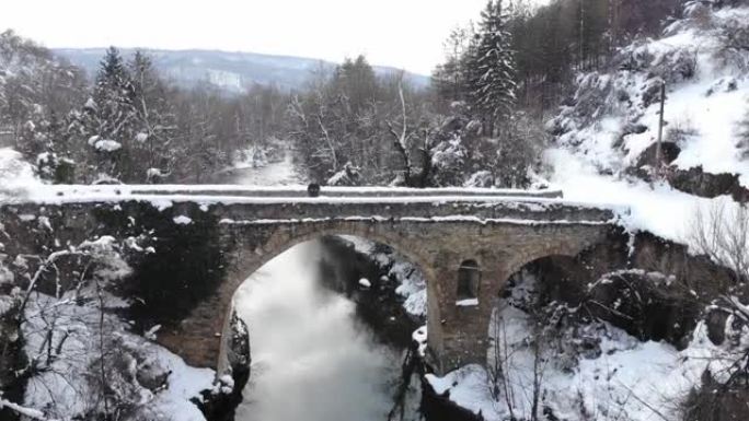 冬季，一名无人机操作员站在历史桥上的4k视频