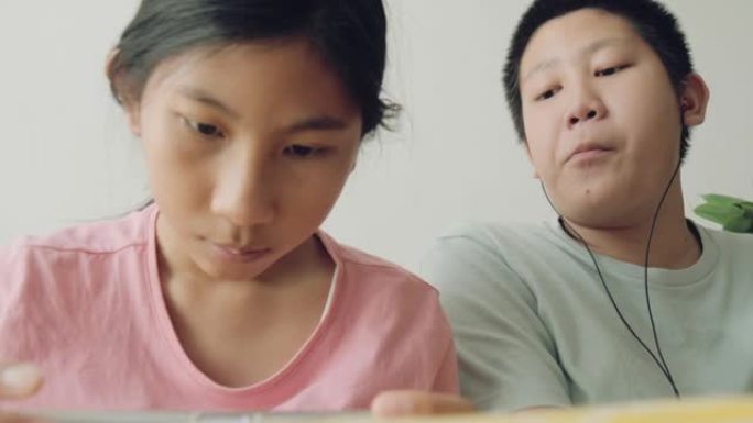 快乐的亚洲儿童在家里坐在沙发上一起在线玩手机游戏，生活方式理念。