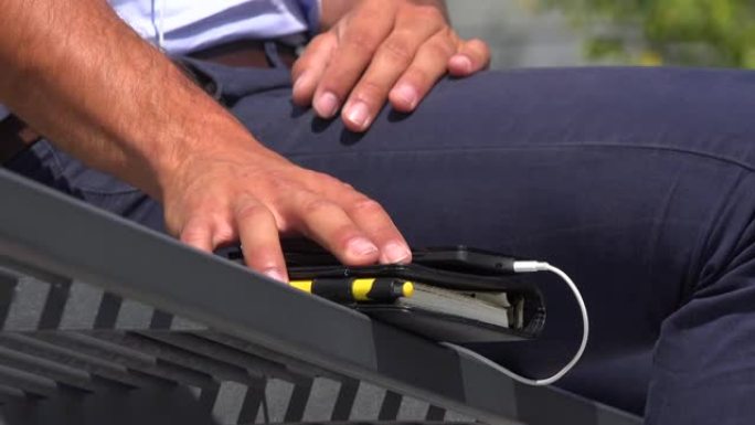 一位商人坐在长凳上听音乐，检查他的智能手机特写镜头