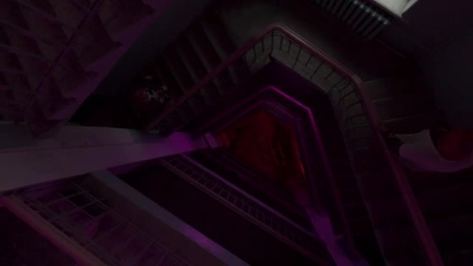 在彩色灯泡闪烁的灯光下，圆形楼梯的俯视图。库存镜头。沿着多层建筑的楼梯飞下，派对和音乐的概念。