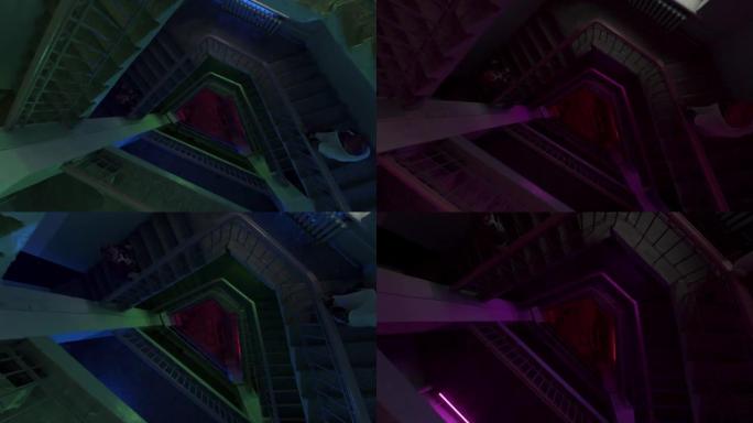 在彩色灯泡闪烁的灯光下，圆形楼梯的俯视图。库存镜头。沿着多层建筑的楼梯飞下，派对和音乐的概念。