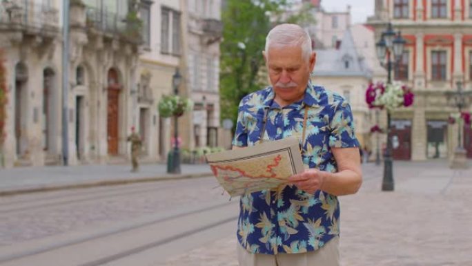 老年时尚旅游祖父男子走在街上，在城市里用纸质地图寻找道路