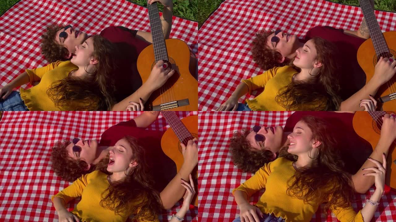 放松的一天 -- 躺在草坪上的年轻夫妇唱歌弹吉他