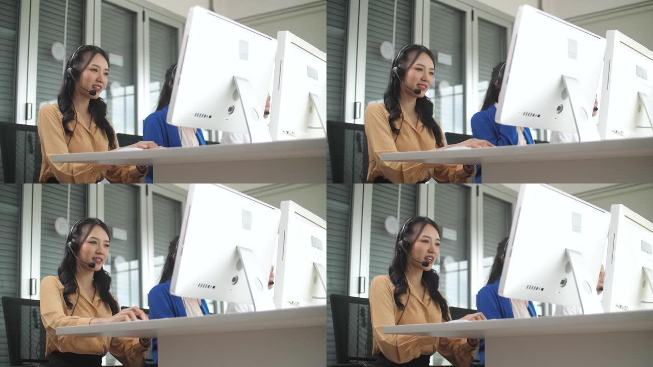 美丽的亚洲女性呼叫中心代理在她的工作站上与客户交谈