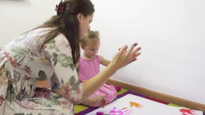一位年轻的母亲和她美丽的小女儿用手指画画。