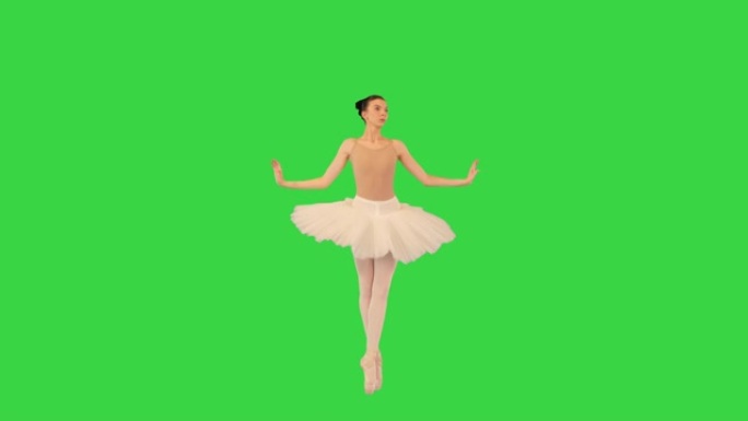 芭蕾舞女演员tip脚走路，在绿色屏幕上挥舞双手，色度键