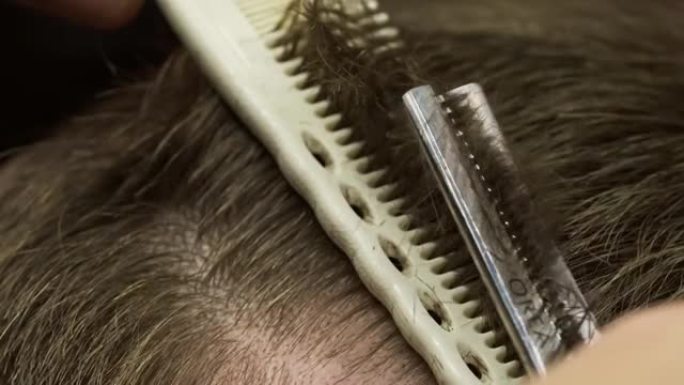 理发师用梳子和剪刀剪头发的特写镜头。