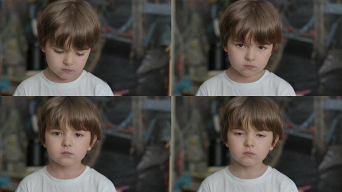 肖像小男孩看着相机。年轻的悲伤思维好奇的孩子在室内看着相机特写。脸眼睛严肃沉思的孩子特写。体贴的小男