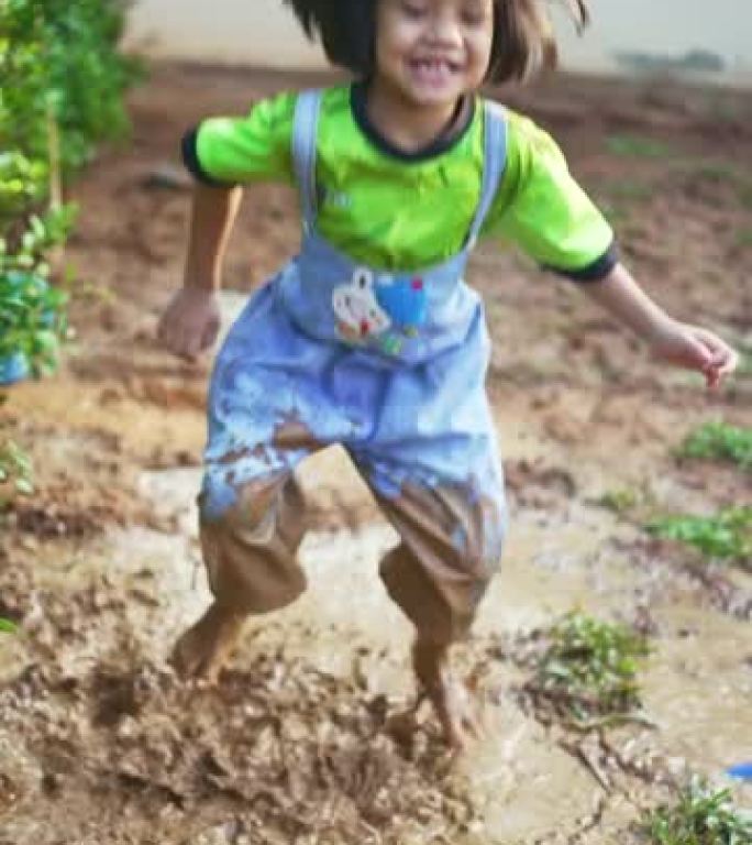 小女孩在非常泥泞的水坑里跳进水坑。