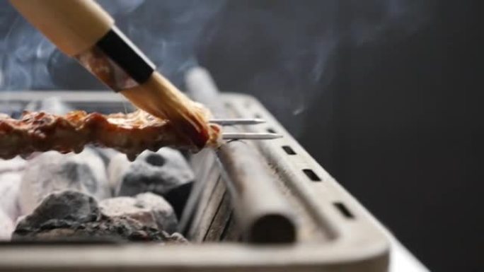 在烟熏木炭hibachi烧烤炉上的猪肚串上刷酱汁后关闭