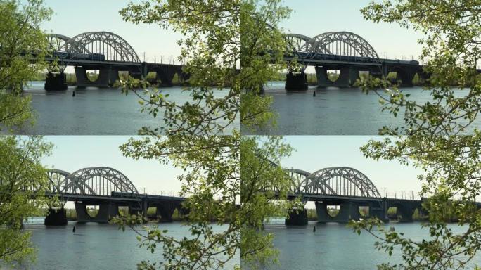 一列旅客列车经过一条宽阔河流上的铁路金属桥。基辅第聂伯河上的船漂浮春天日落。货船在平静的湖上航行。乌